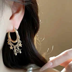 Elegante goldene Creolen mit Sternanhängern und Kettenquasten an einem Modell