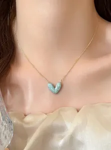 Detailansicht einer eleganten Halskette mit blauem marmoriertem Herzanhänger und Goldkette