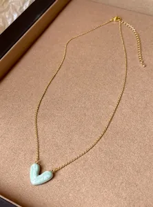 Detailansicht eines hellblauen marmorierten Herzanhängers an einer feinen Goldkette