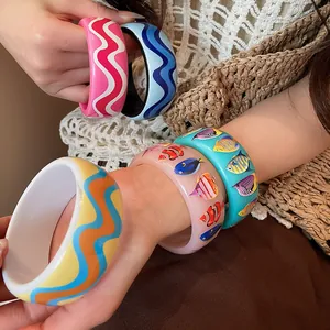 Detail view of colorful resin bangles with fish prints and wavy patterns for beach style