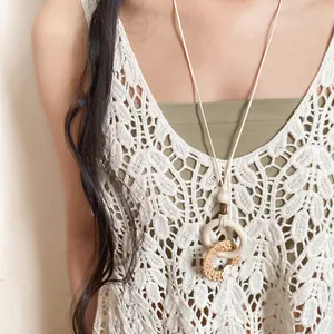 Close-up detail of a bohemian style rattan and wooden double ring pendant necklace on model