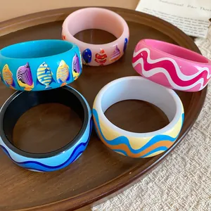 Detail shot of colorful resin bangles with tropical fish and wave print patterns.