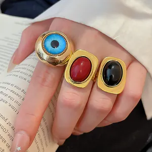 Nahaufnahme von Vintage-Resin-Ringen in Gold mit blauem Auge und roten Akzenten