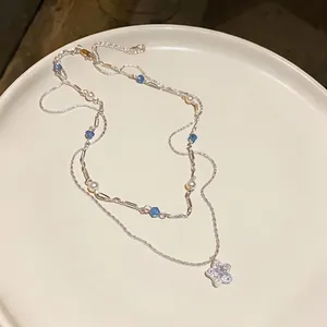 Elegant double-layered necklace featuring a zircon star pendant, pearls, and blue beads
