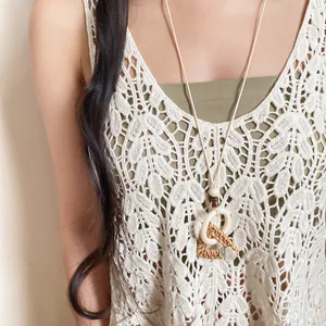 Bohemian handcrafted rattan and wood ring necklace worn on a white lace crochet top