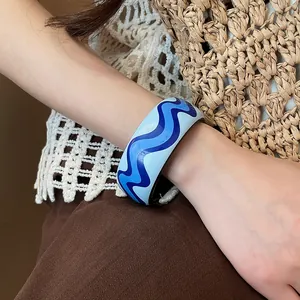 Close-up of a trendy blue wavy pattern resin bangle worn on wrist for seaside holiday style