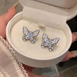 Close-up detail of silver hollow butterfly ear clips with sparkling zircon stones