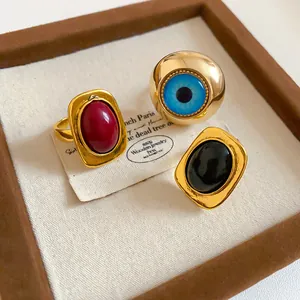 Nahaufnahme von Vintage-Goldringen mit ovalem Harz und Evil-Eye-Design in Schmuckschatulle.