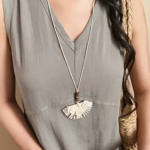 Close-up of bohemian style white woven lace pendant necklace with wooden beads on model
