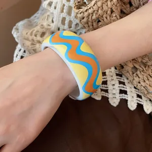 Close-up of a colorful wavy pattern resin bangle on a wrist for resort style