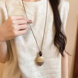 Dettaglio di una collana lunga neo-cinese con ciondolo a ghianda a motivi irregolari.