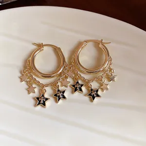 Detailaufnahme goldene Creolen mit Kettenquasten und schwarzen Emaille-Sternen