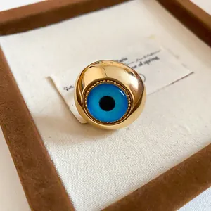 Detailansicht eines Vintage-Goldrings mit einem lebhaften blauen Harz-Auge in der Mitte.