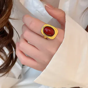 Detailansicht eines vintage ovalen Harzrings in goldener Hammerschlag-Optik am Finger