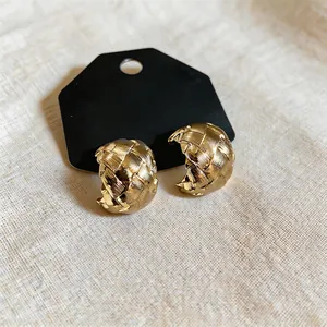 Detailed view of 18k gold plated woven C-shaped clip-on earrings with a textured finish