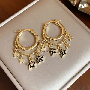 Nahaufnahme goldener Sternen-Ohrringe mit schwarzen Emaille-Anhängern und Ketten