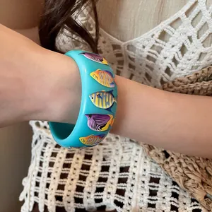 Detail view of beach style resin bangle with colorful tropical fish prints