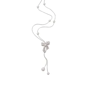 Vintage silver hollow bow lariat necklace with white pearls on plain white background