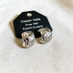 Macro view of silver-toned woven textured C-shaped clip-on earrings on display card