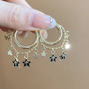 Detailansicht von goldenen Creolen mit schwarzen Sternen und langen Fransenketten
