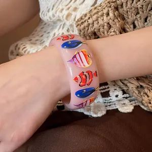 Detailed view of a semi-transparent pink resin bracelet featuring vibrant tropical fish patterns