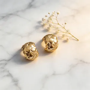 Detailed macro view of 18k gold plated woven C-shaped ear clips on marble background