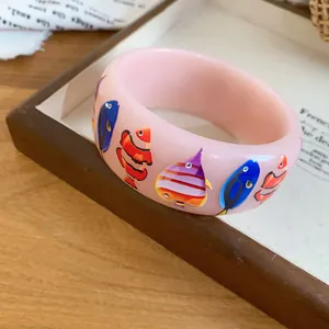 Macro detail of the colorful fish print on a smooth pink resin bangle bracelet