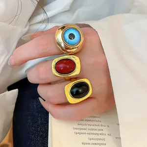 Detailansicht von Vintage-Resinringen an den Fingern mit einem blauen Augen-Design.