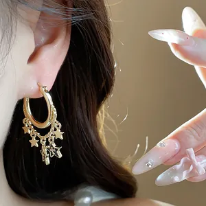 Detailansicht goldener Creolen mit Sternanhängern und schwarzer Emaille am Modellohr