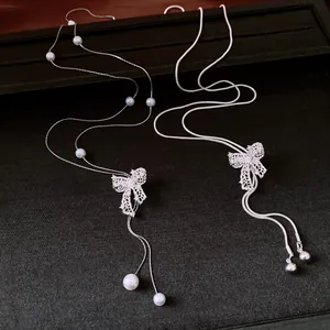 Detailed view of vintage silver hollow bow necklace with pearls on black background