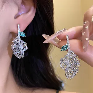 Close-up detail of silver needle earrings with hollow leaf design and sparkling zircon stones