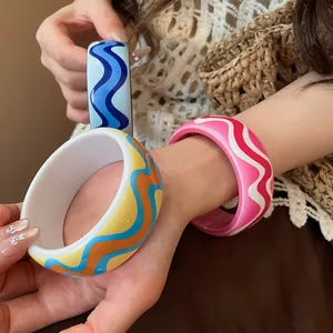 Close-up of vibrant resin bangles with wavy printed patterns for a resort style look