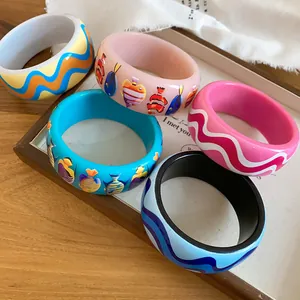 Macro detail of colorful resin bangles with tropical fish and wave prints for summer