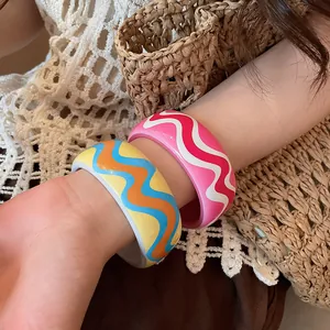 Close-up detail of colorful resin bangles with wavy pattern prints worn on an arm