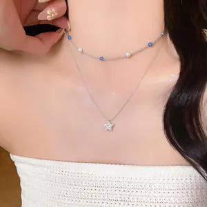 Close-up of elegant double-layered necklace with zircon star pendant and blue pearl beads