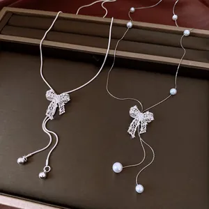 Close-up of vintage silver hollow bow necklace with pearl and bead details