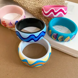 Detailed view of colorful resin bangles with printed tropical fish and wave patterns