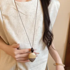 Dettaglio di una collana con pendente a ghianda minimalista per un moderno stile cinese