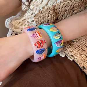 Close-up of colorful tropical fish print resin bracelets for a seaside vacation vibe.