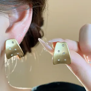 Macro view of brushed 18k gold plated stud earrings with sparkling zircon accents details