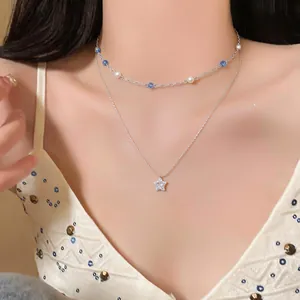 Detailed view of a layered necklace with pearl, blue beads, and a sparkling star pendant.