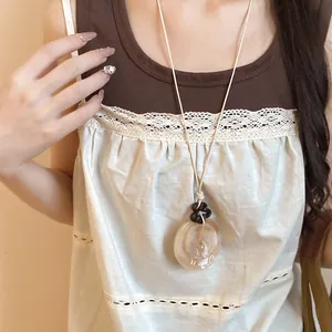Primo piano di una collana con pendente lungo in resina irregolare in stile neo-cinese