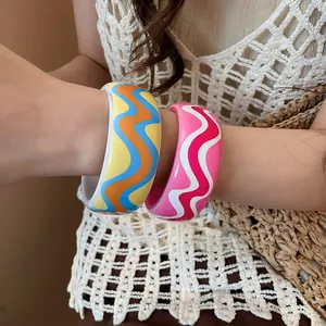 Detail shot of colorful resin bangles with vibrant wavy patterns worn on a model's arm