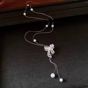 Detailed close-up view of vintage silver hollow bow necklace accented with elegant white pearls