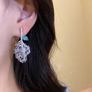 Close-up of sparkling zircon leaf earring with green accents worn by a female model