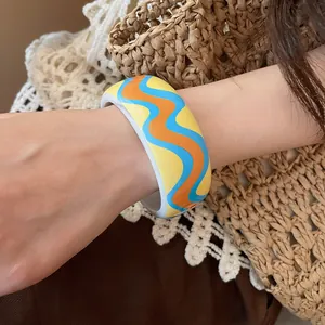 Detail view of colorful wavy pattern resin bracelet on wrist for beach vacation style.
