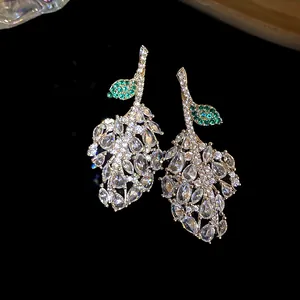 Detailed macro shot of elegant silver leaf earrings with white and green zircons