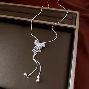 Close-up of vintage silver hollow bow necklace with adjustable beads on jewelry tray.