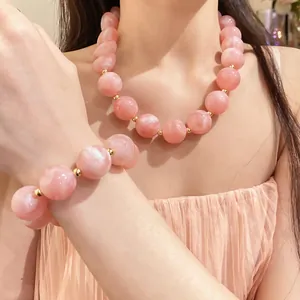 Nahaufnahme eines eleganten Halsketten- und Armbandsets aus rosa Acrylperlen bei einem Modell