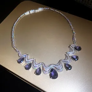 Detail view of sparkling water-drop purple zircon necklace on gold surface
